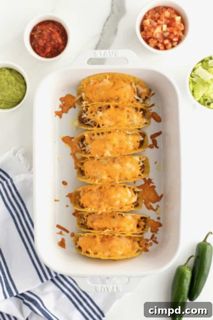 Plated Beef and Bean Baked Taco with toppings including lettuce, pico de gallo, and guacamole, by The BakerMama