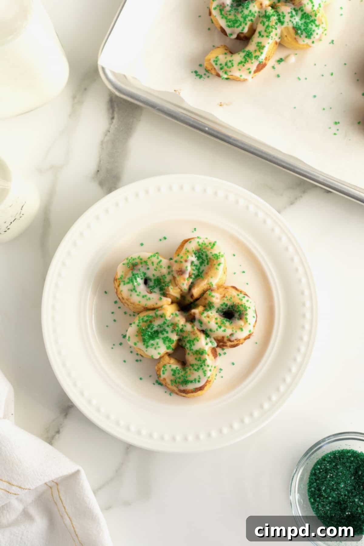 St. Patrick's Day Cinnamon Rolls arranged in clover shapes on a baking sheet before baking