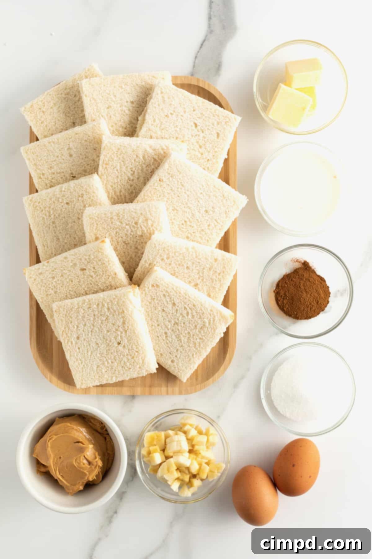 Overhead shot of ingredients laid out: bread, peanut butter, banana, eggs, milk, cinnamon, sugar, and butter.