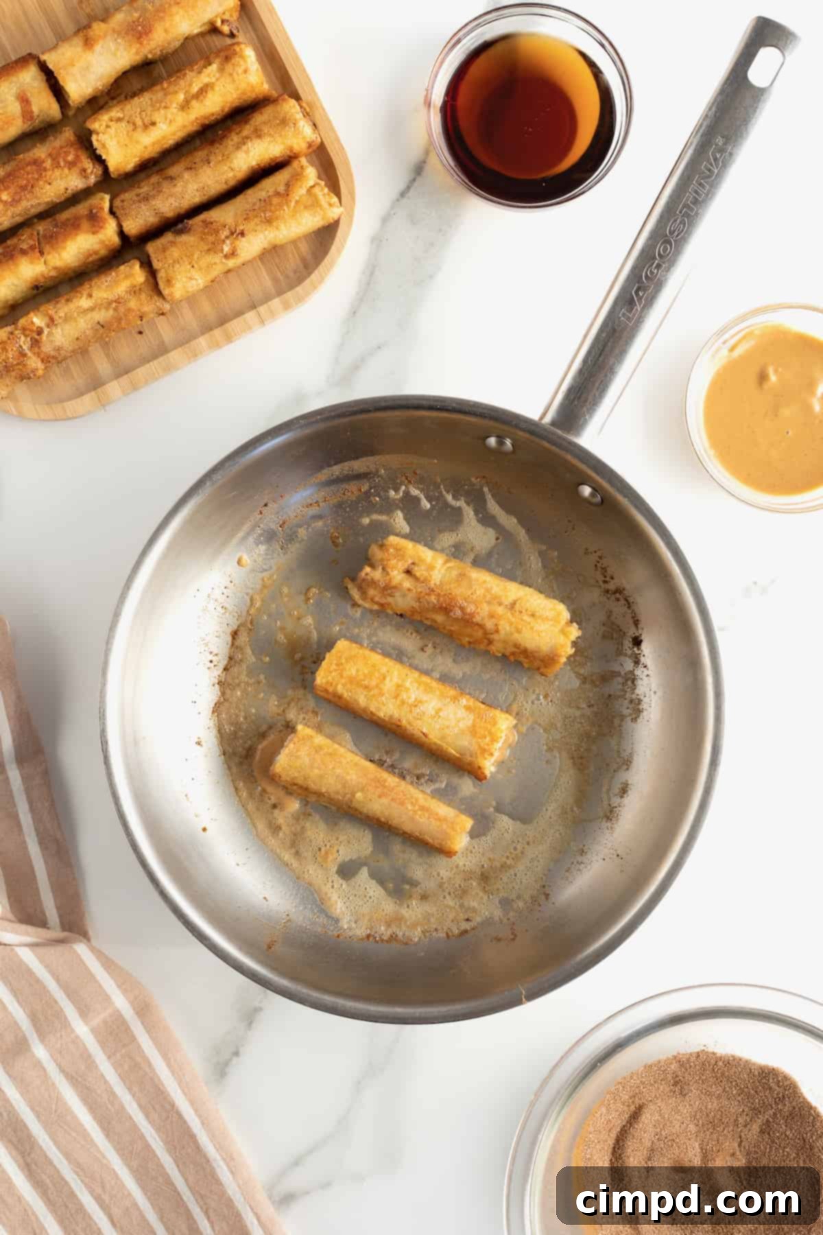 Pan-fried Peanut Butter Banana French Toast Roll Ups being tossed in cinnamon sugar.
