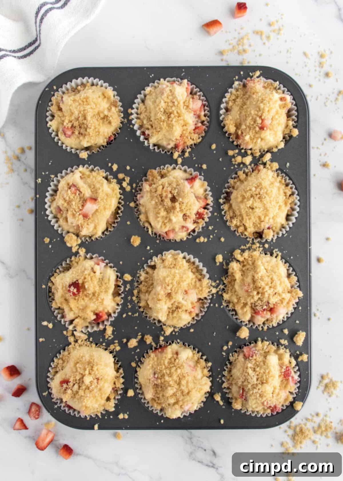 Strawberry streusel muffins in a baking tin, ready to go into the oven