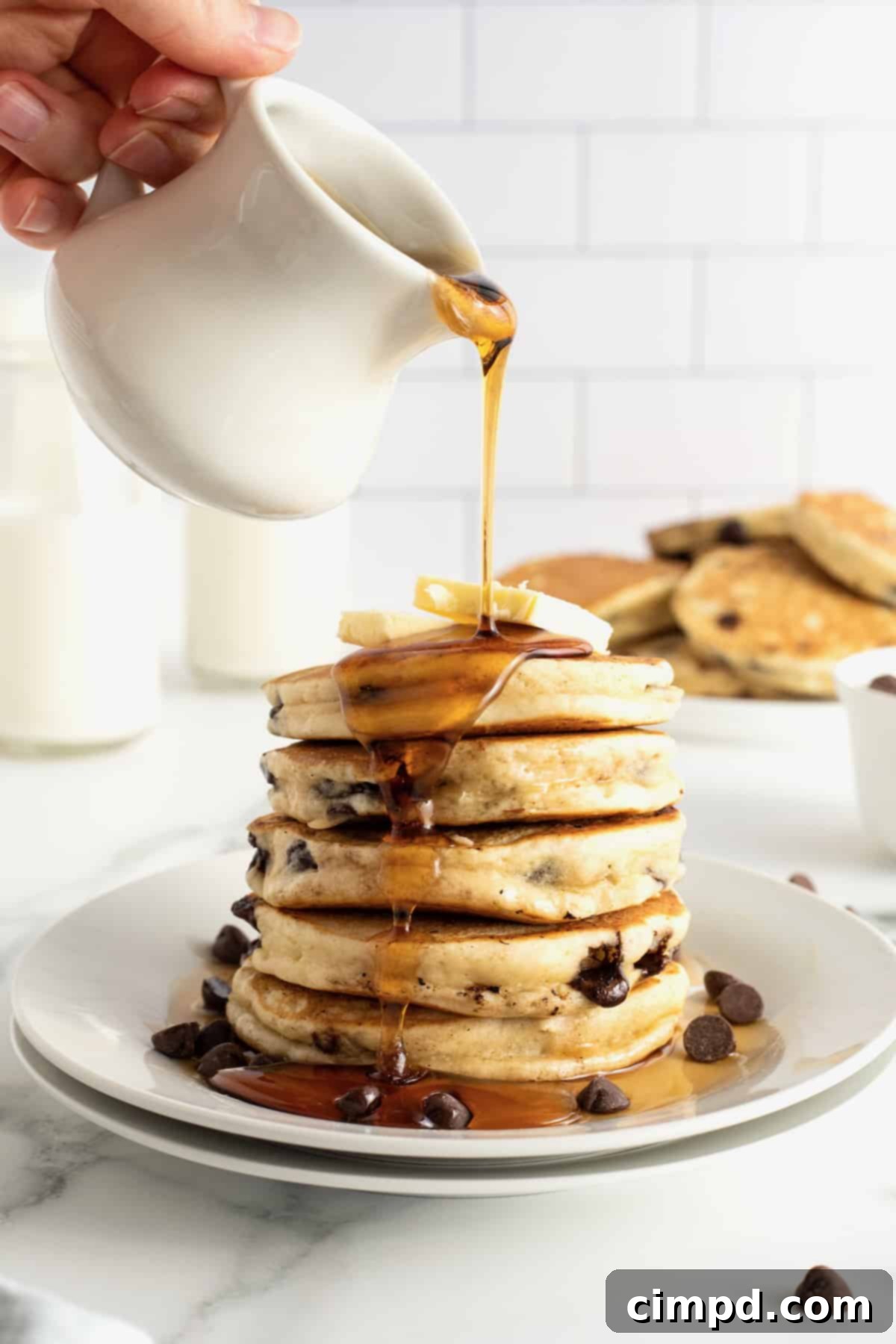Stack of chocolate chip pancakes garnished with butter and syrup