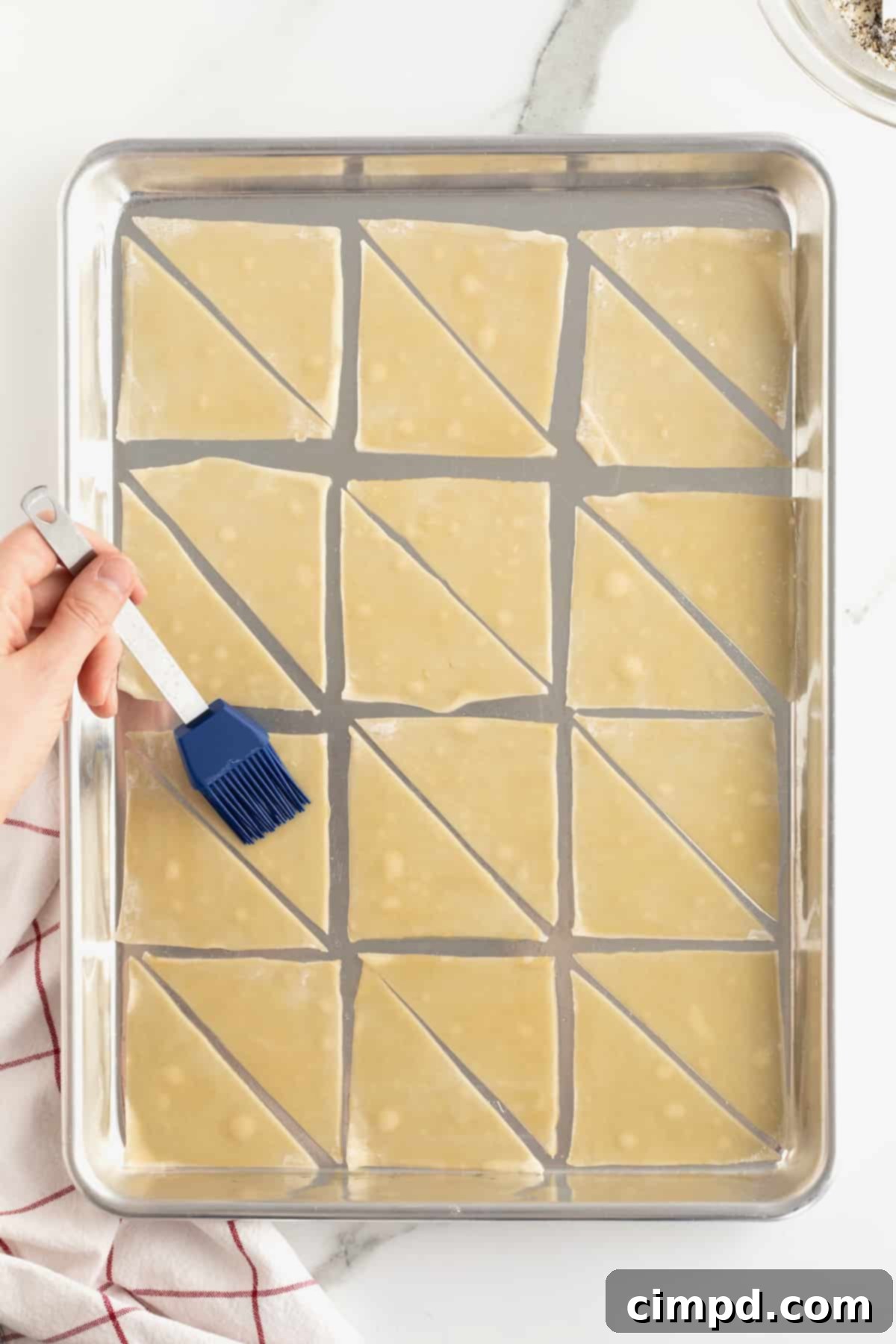 Step-by-step: arranging and brushing wonton halves with sesame oil on a baking sheet