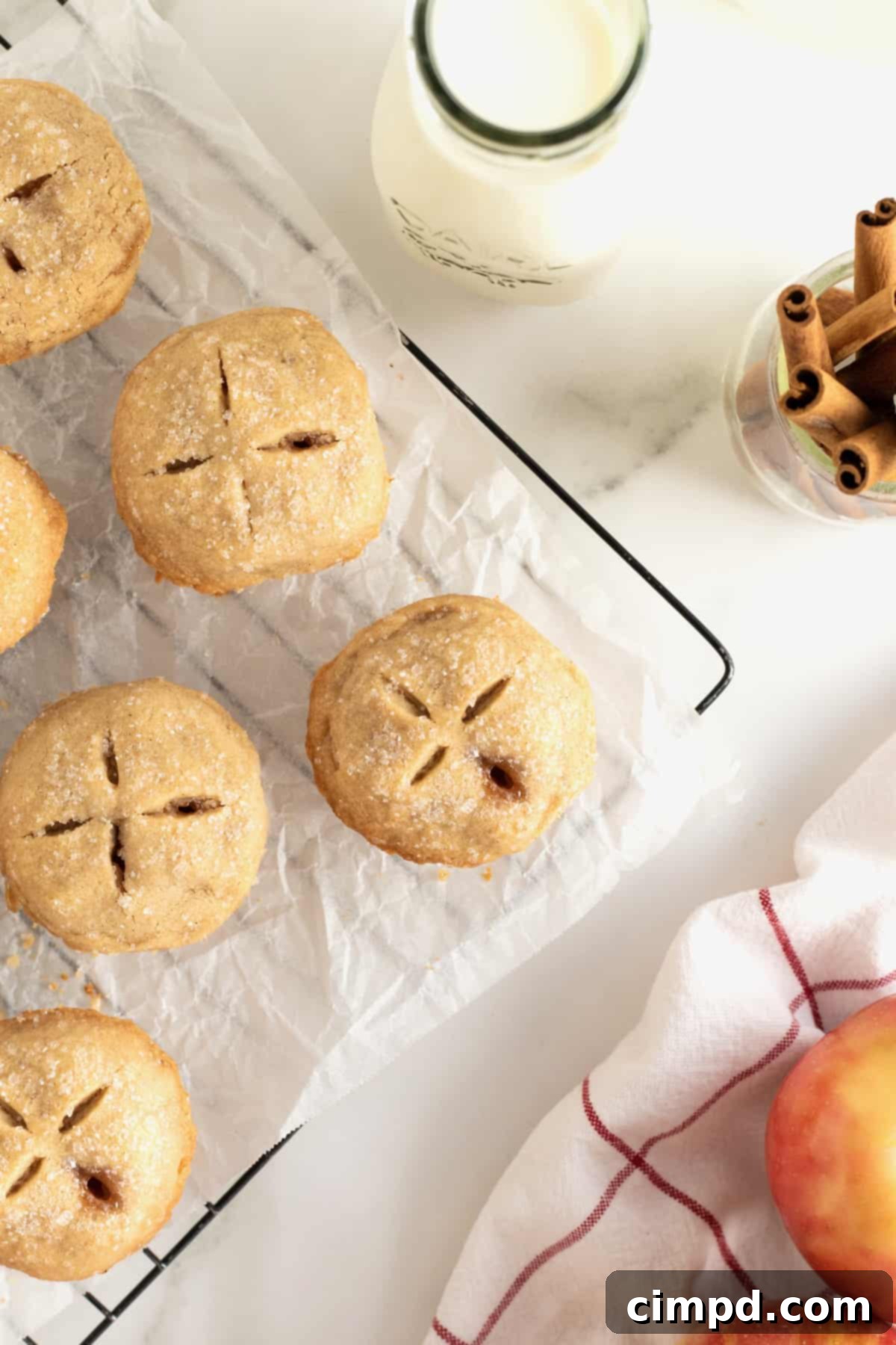 Six apple pie bites on a parchment-lined wire cooling rack.