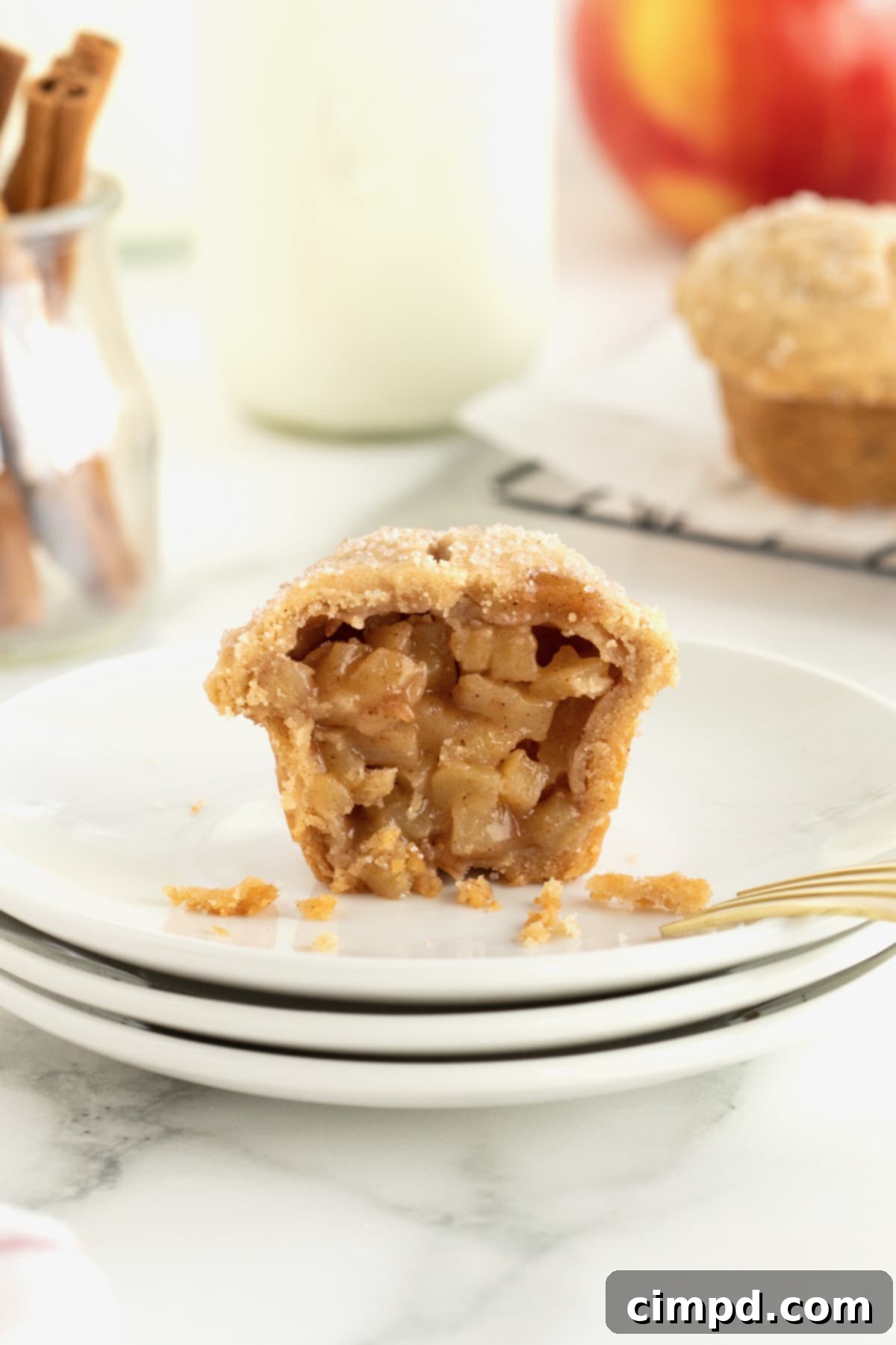 A two-bite apple pie cut in half on a stack of small white plates.