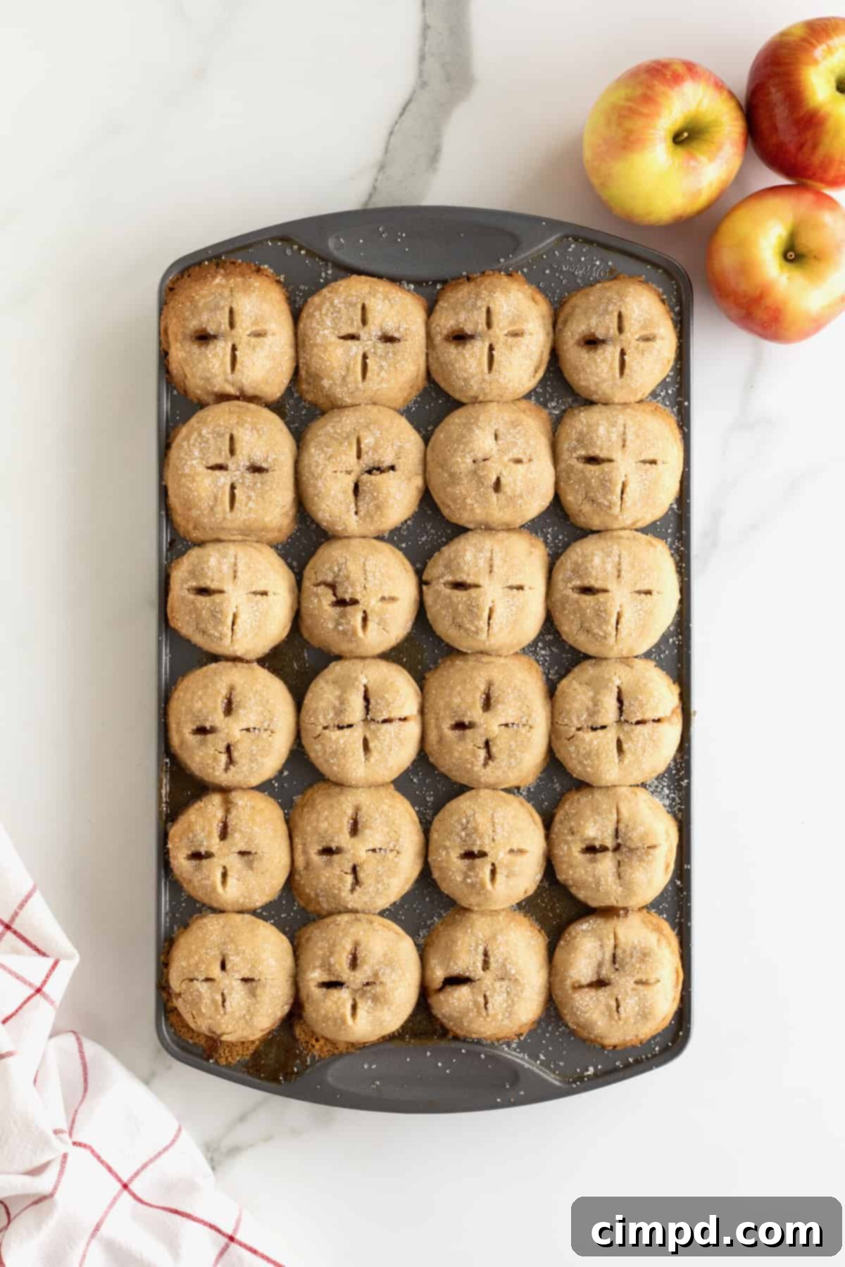 An aluminum mini muffin pan with filled 24  apple pie bites.