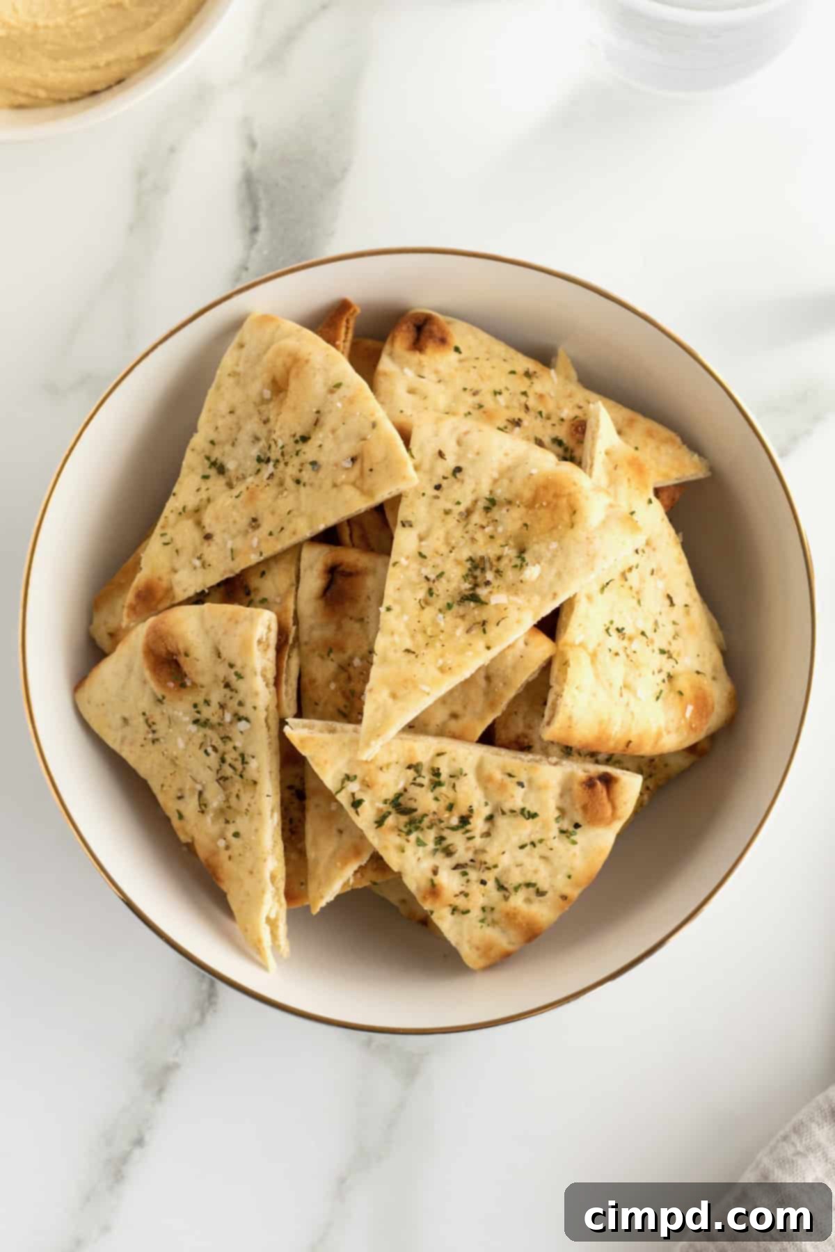 A bowl of freshly baked pita chips with hummus