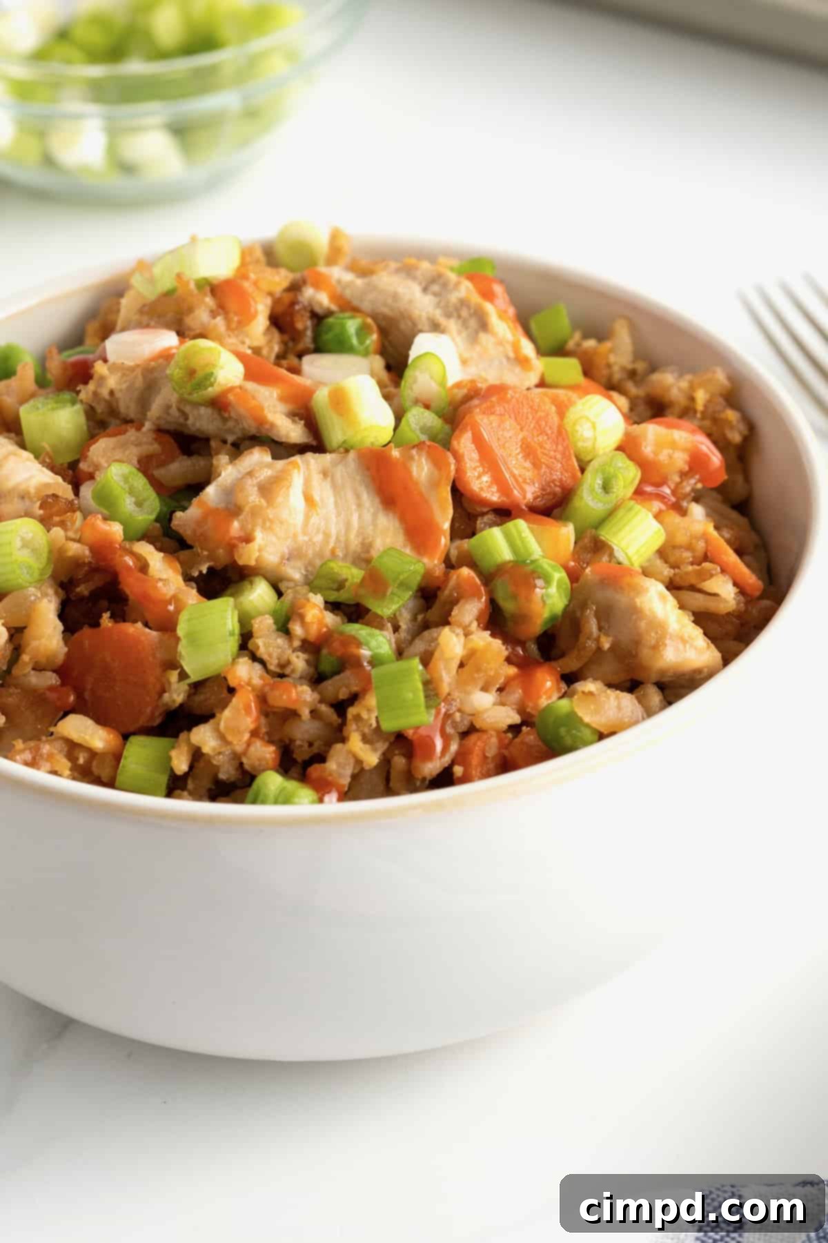 A bowl of Sheet Pan Chicken Fried Rice with chopsticks, ready to be enjoyed