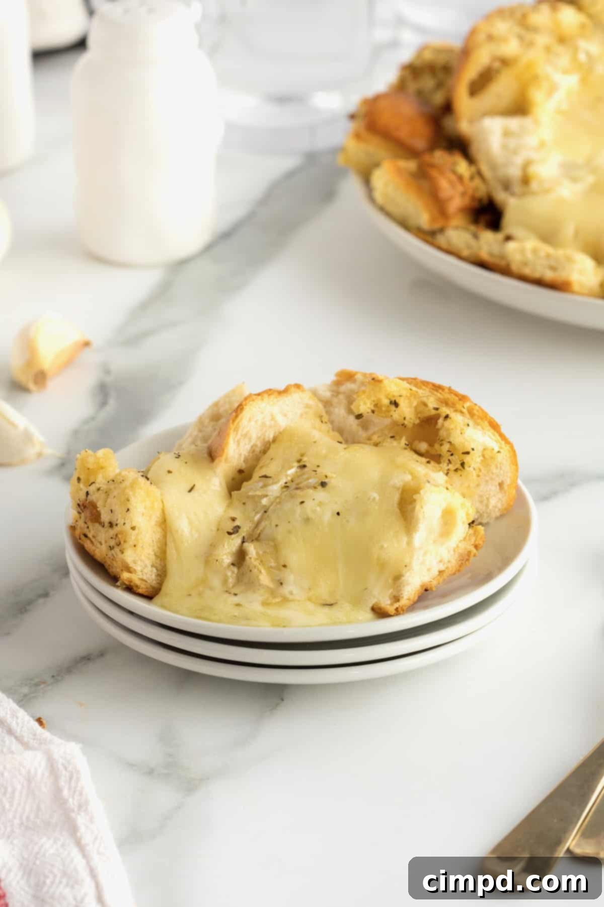 Melted brie in a bread bowl on a white plate.
