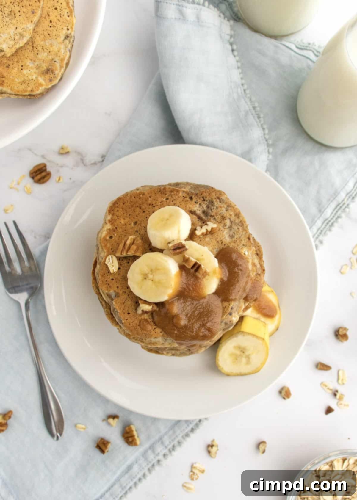 Wholesome Banana Nut Oat Pancakes 6 A stack of Whole Wheat Banana Nut Oat Pancakes with a generous drizzle of peanut butter maple syrup