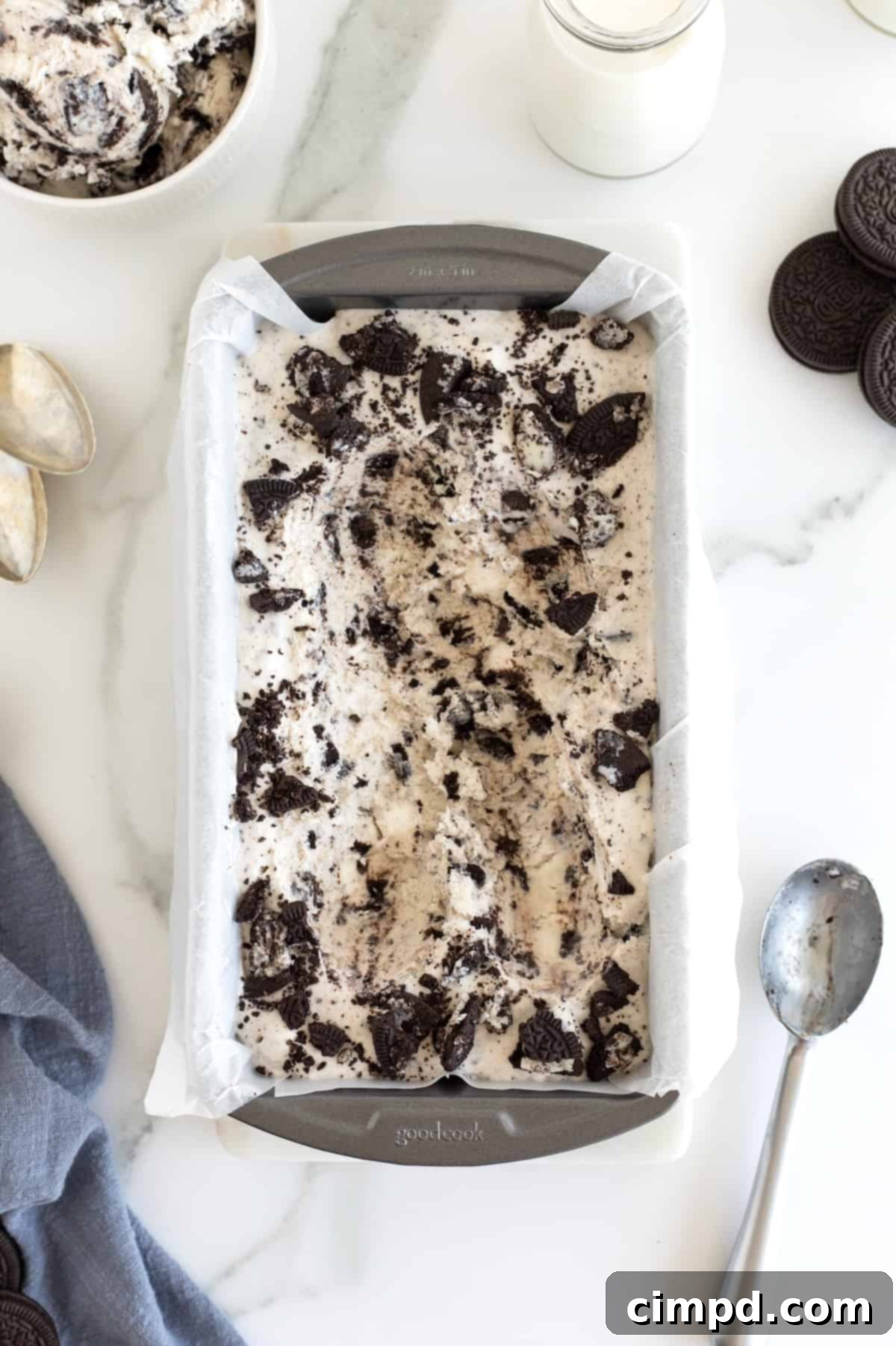 Black and White Bliss 12 A gleaming metal spoon resting beside the perfectly frozen Cookies and Cream ice cream in a loaf pan, lined with parchment paper, tempting a taste.