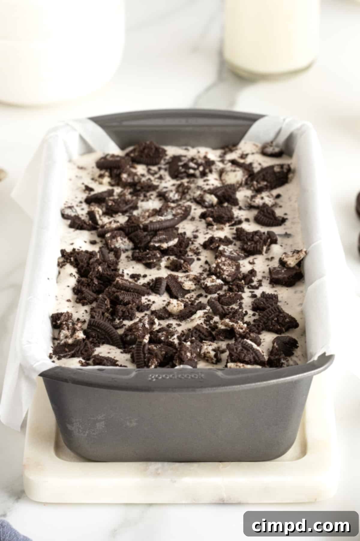 Black and White Bliss 4 Decadent Cookies and Cream ice cream, freshly prepared and nestled in a loaf pan lined with parchment paper, awaiting its perfect freeze.