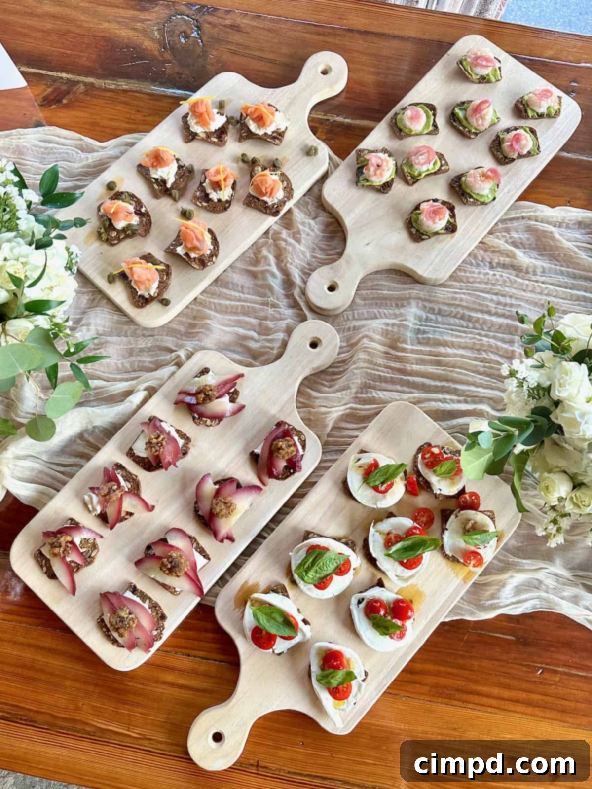 Four natural wood cutting boards laden with an inviting variety of cracker bites, ready for guests to assemble.