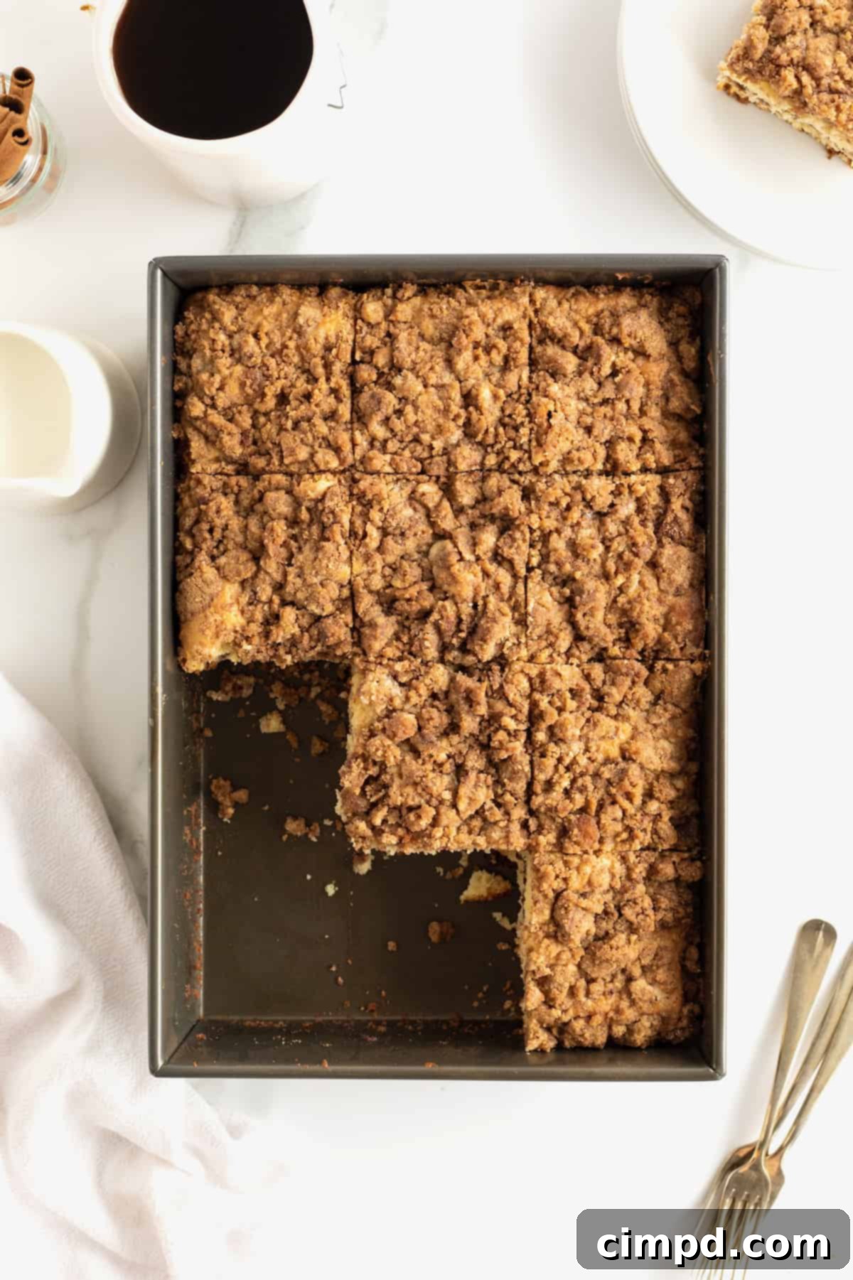 A rectangle metal baking pan of coffee cake with three slices already cut and removed.