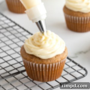 Whip Up Perfect Cream Cheese Frosting 9 Cream cheese frosting piped onto a cupcake resting on a wire cooling rack.