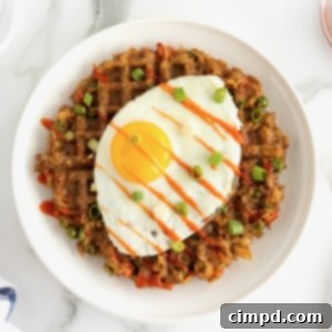 A sunny side up egg on top of a fried rice waffle on a white ceramic plate.