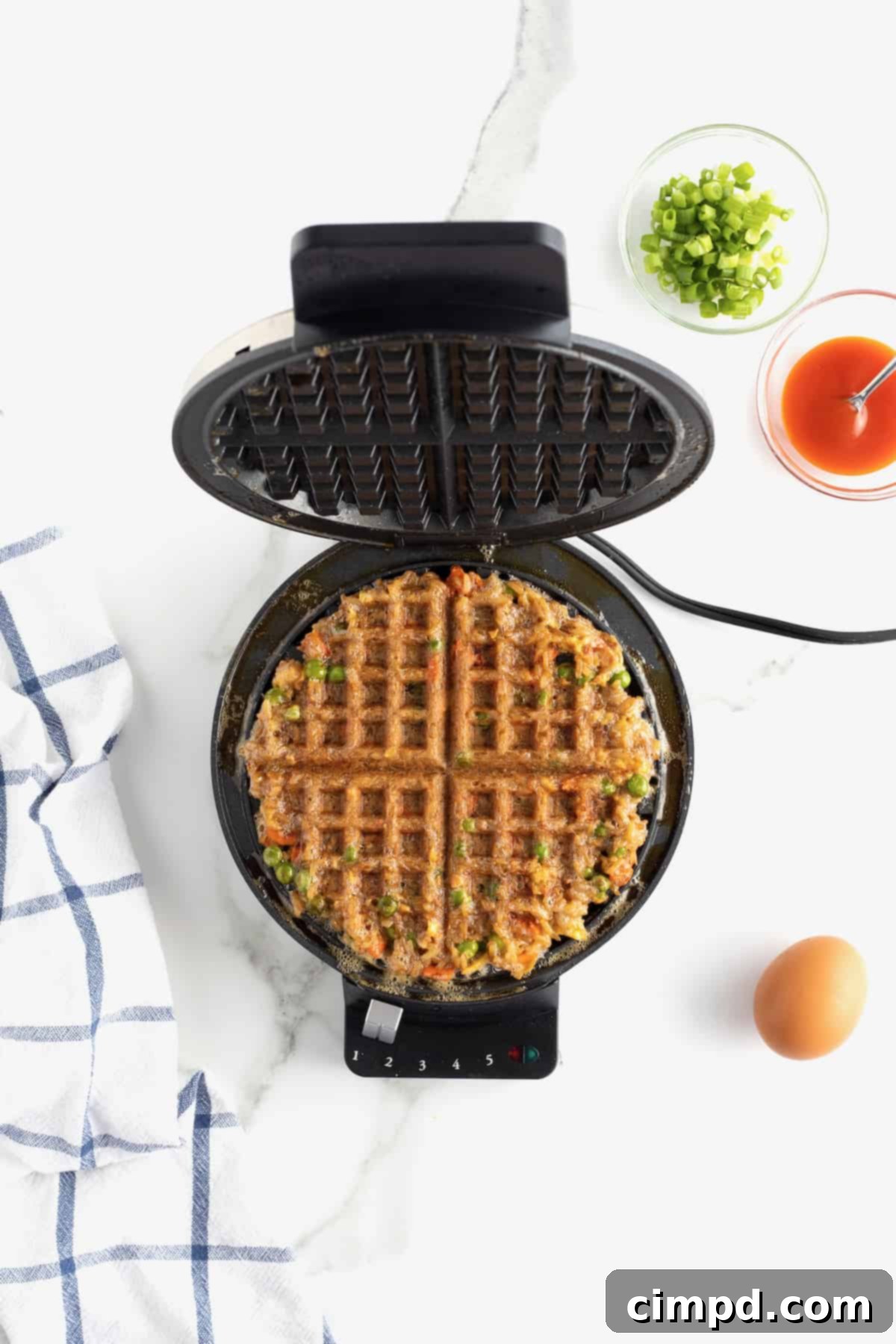 A perfectly cooked, golden-brown fried rice waffle resting on an open waffle iron.