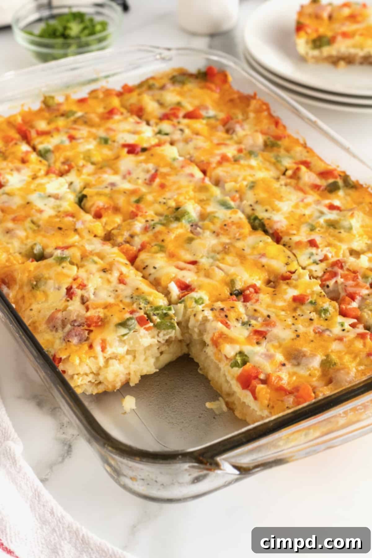 A clear glass baking dish with hash brown breakfast casserole, fresh out of the oven, steam gently rising.