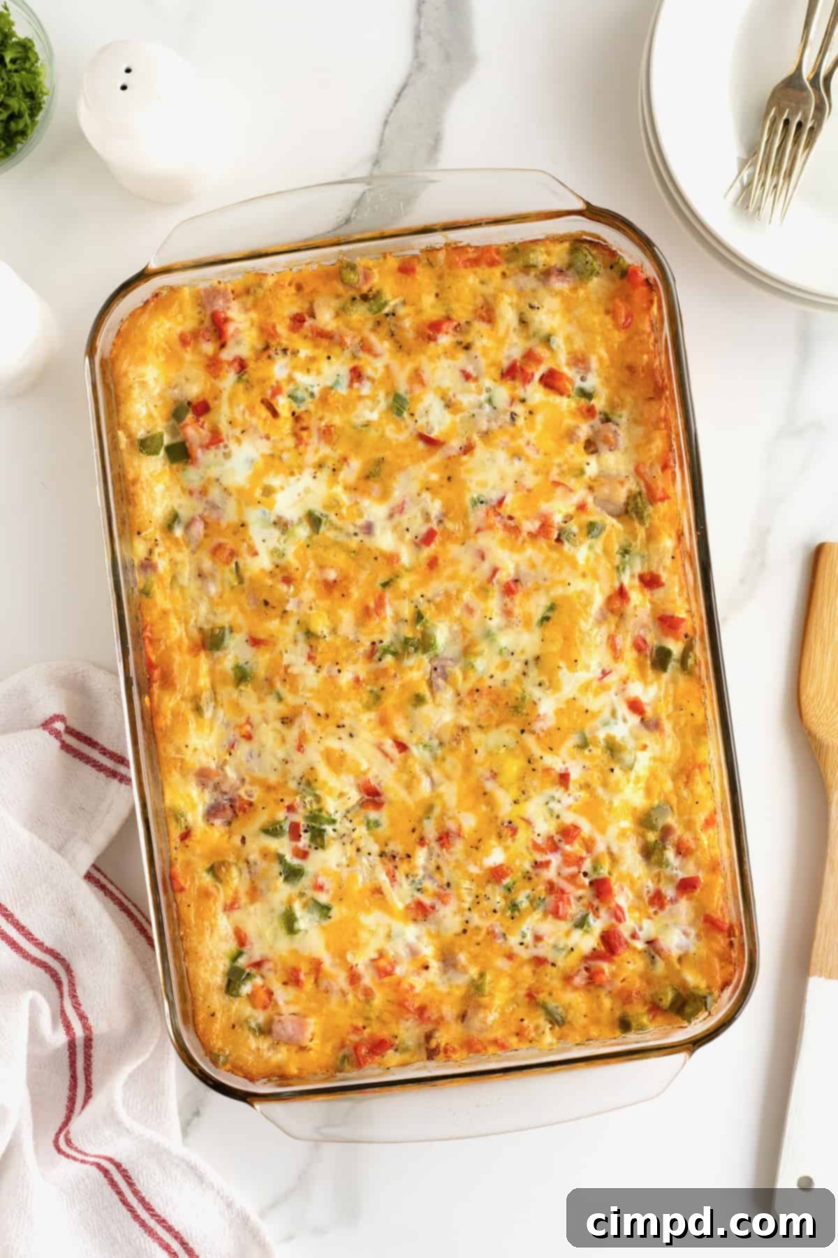 A fully cooked breakfast casserole in a clear glass dish, with a wooden spatula resting nearby, highlighting its golden crust and inviting texture.
