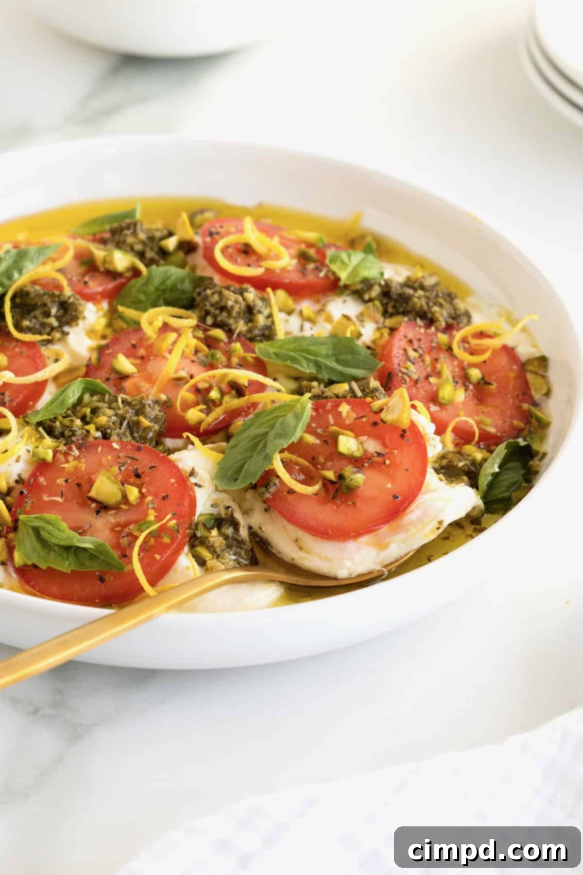 Velvet Burrata Caprese Board 4 A beautifully arranged Burrata Caprese platter in a white serving dish, ready to be enjoyed.