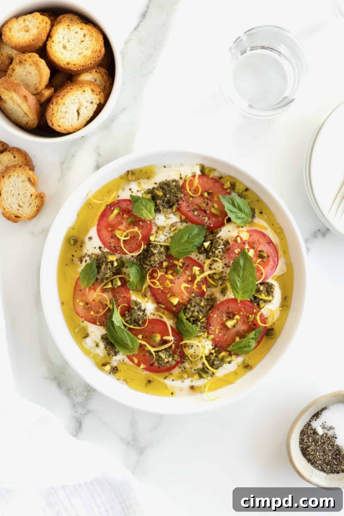 Velvet Burrata Caprese Board 10 The final step of topping the burrata caprese with fresh basil leaves for garnish.