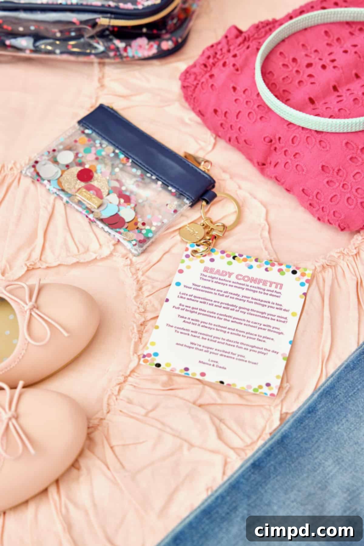 Ignite Your School Year 5 A small, glitter-filled keychain pouch rests beside a pair of child's pink ballet flats and a bright pink eyelet lace shirt, all placed on a soft, ruffled pale pink bedspread.