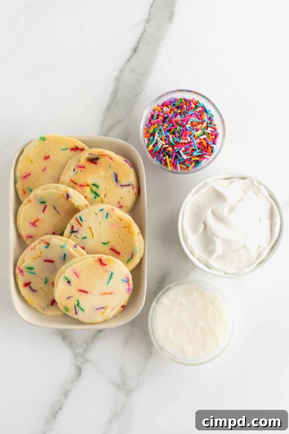 Celebration Pancake Stack 5 Confetti pancakes, a bowl of rainbow sprinkles, a bowl of whipped cream and a bowl of icing.