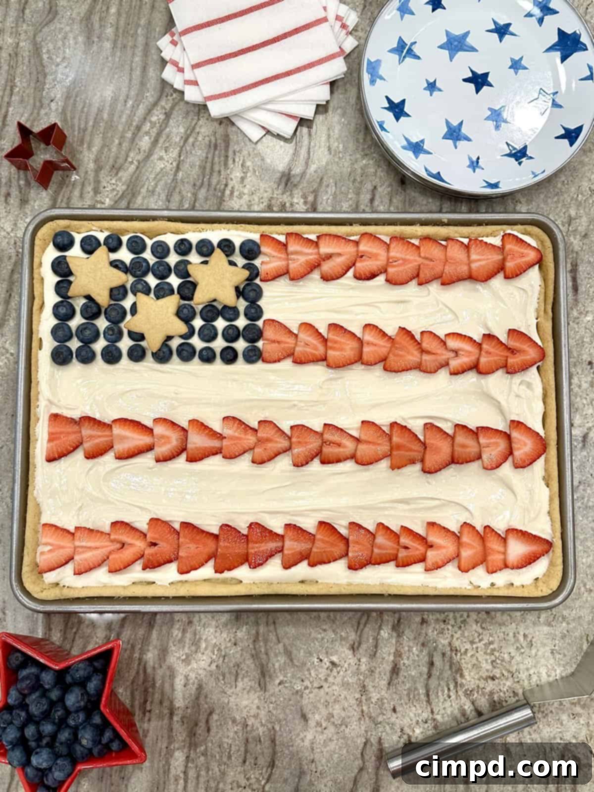 Star-Spangled Fruit Pizza with Cream Cheese Frosting 2 A festive American Flag Fruit Pizza, featuring a sugar cookie base, cream cheese frosting, and arranged with sliced strawberries, fresh blueberries, and star-shaped sugar cookies.