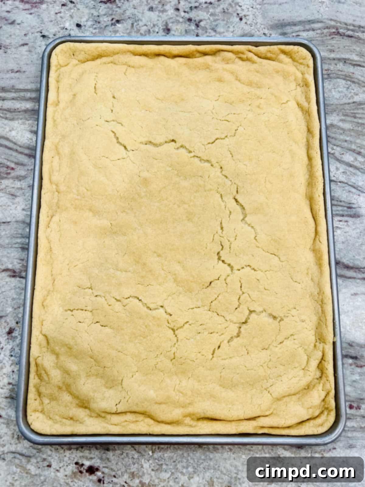 Star-Spangled Fruit Pizza with Cream Cheese Frosting 4 A baked sheet pan sugar cookie, golden brown and ready for frosting, forming the base of the American Flag Fruit Pizza.