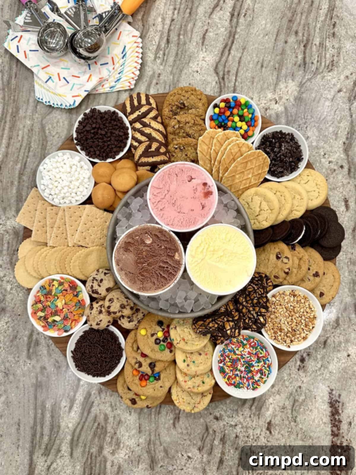 DIY Cookie Ice Cream Sandwich Bar 2 A large wooden board with chocolate, strawberry and vanilla ice creams, various cookies, and an assortment of toppings like mini marshmallows, M&Ms, crushed Oreos, rainbow sprinkles, Fruity Pebbles, and crushed peanuts, ready for assembly.