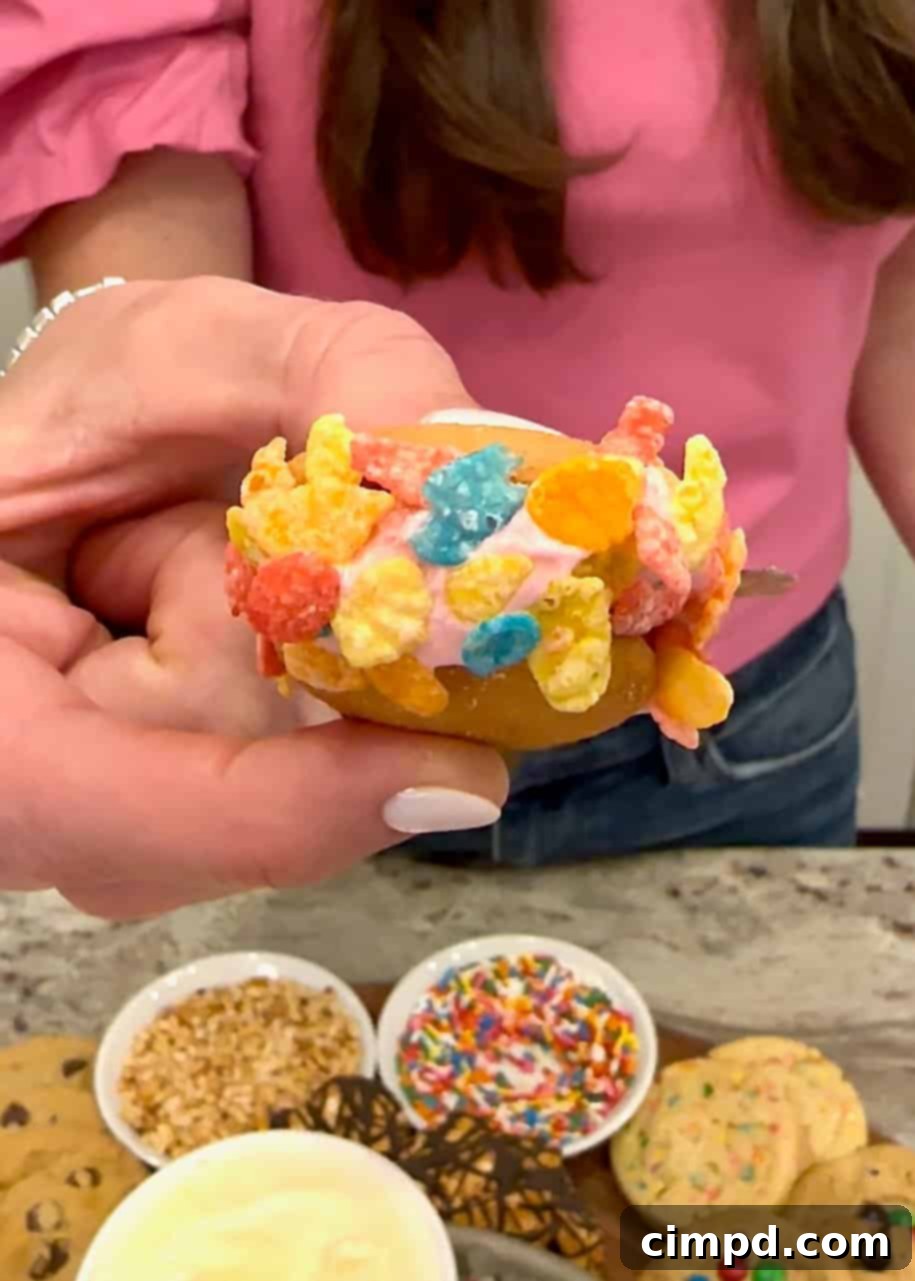 DIY Cookie Ice Cream Sandwich Bar 5 Two Nilla wafers sandwiching a scoop of strawberry ice cream, generously coated in vibrant Fruity Pebbles cereal.