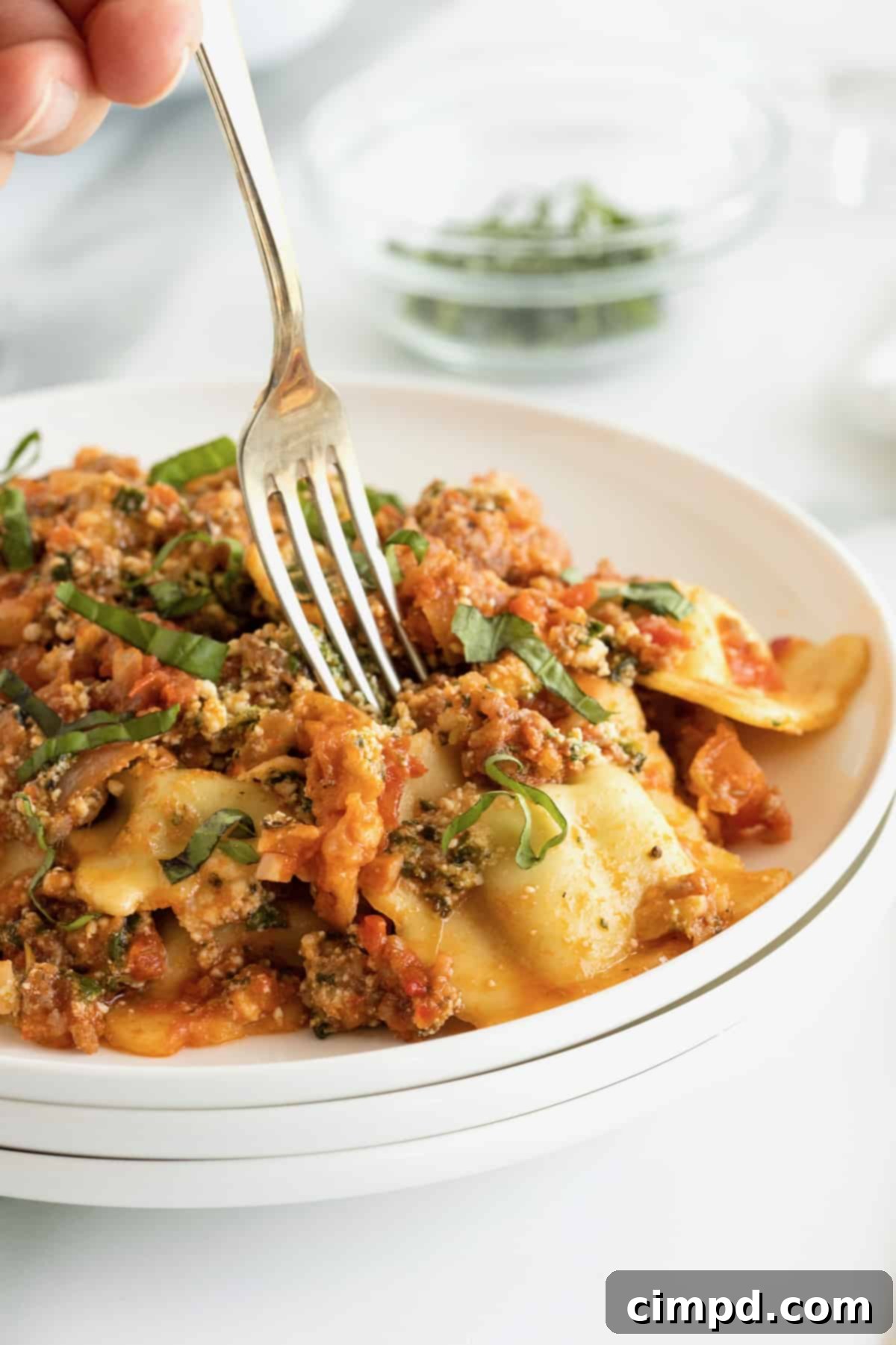 A fork going into a serving of lasagna on a white dinner plate.