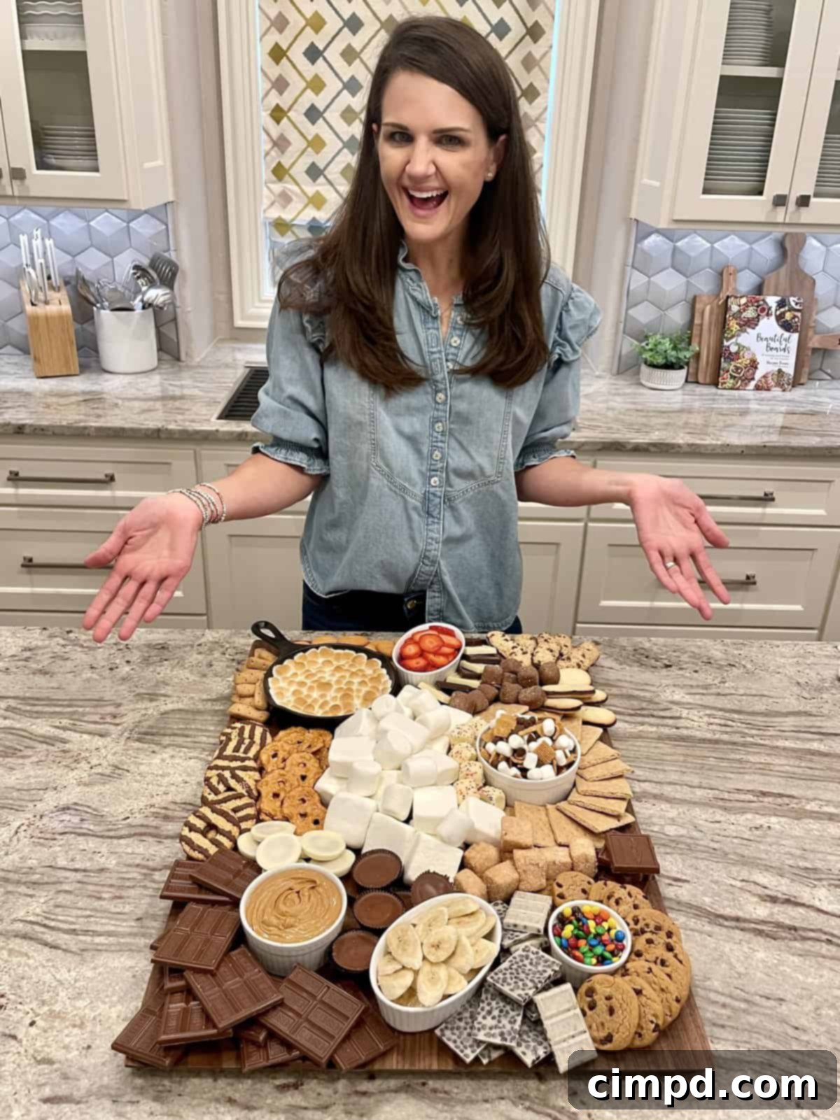 Your Guide to an Epic Smores Board 3 A beautifully arranged wooden board featuring a rich variety of s'mores components: graham crackers, different types of marshmallows, Fudge Stripe cookies, a bubbling S'mores skillet dip, fresh slices of strawberries and bananas, savory pretzel chips, and classic chocolate chip cookies, ready for assembly.