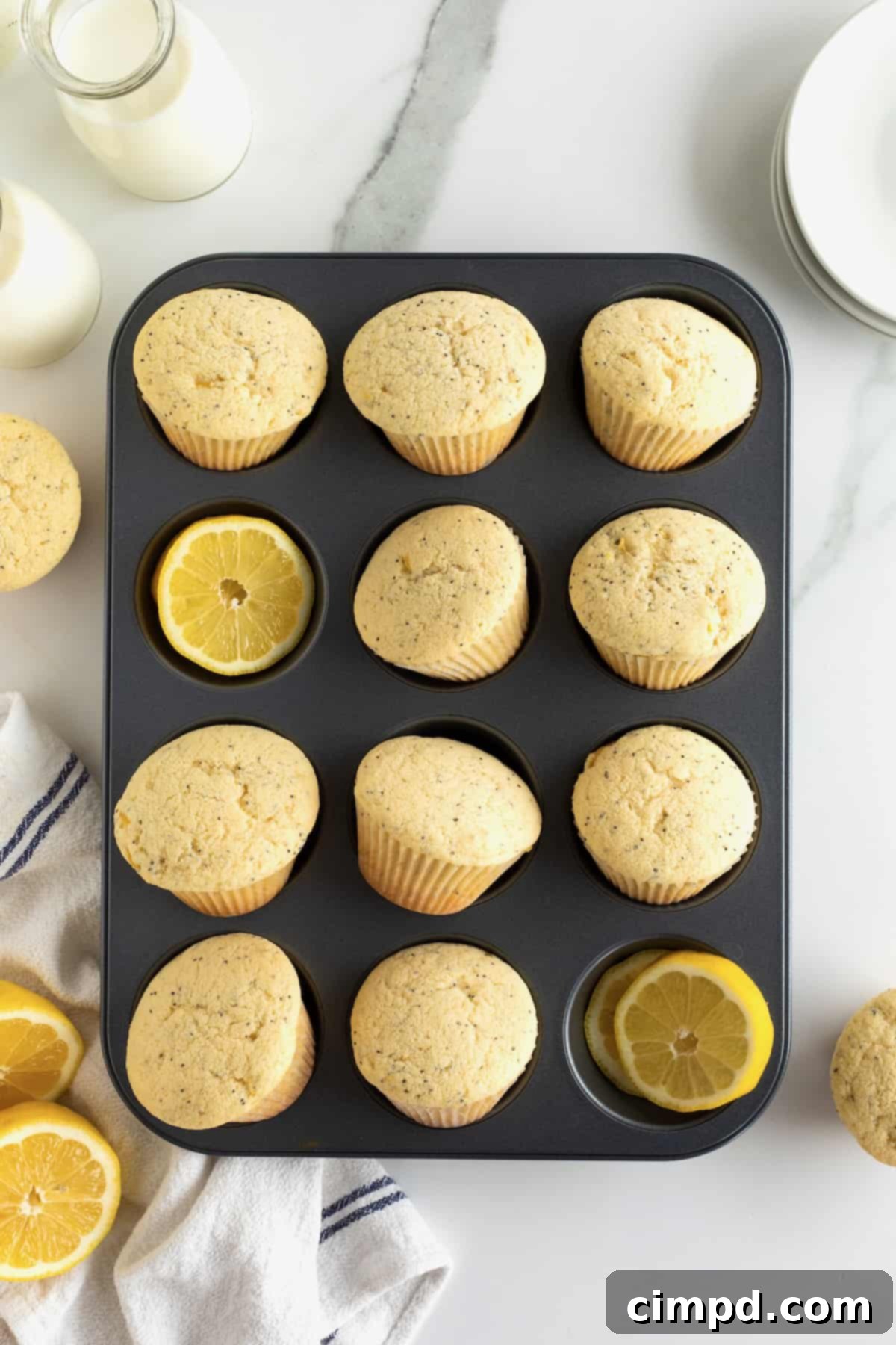Zesty Lemon Poppy Seed Delights 4 A dozen golden lemon poppy seed muffins baked in a muffin pan, with fresh lemon halves scattered around.