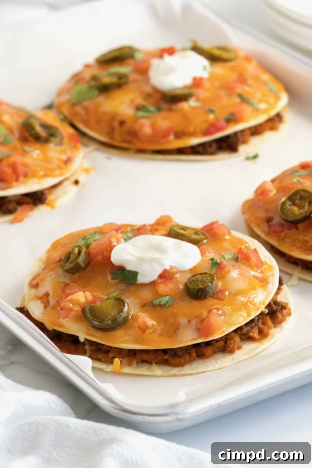 Pizzas made from tortillas with melted cheese, sliced jalapeño, and topped with sour cream.