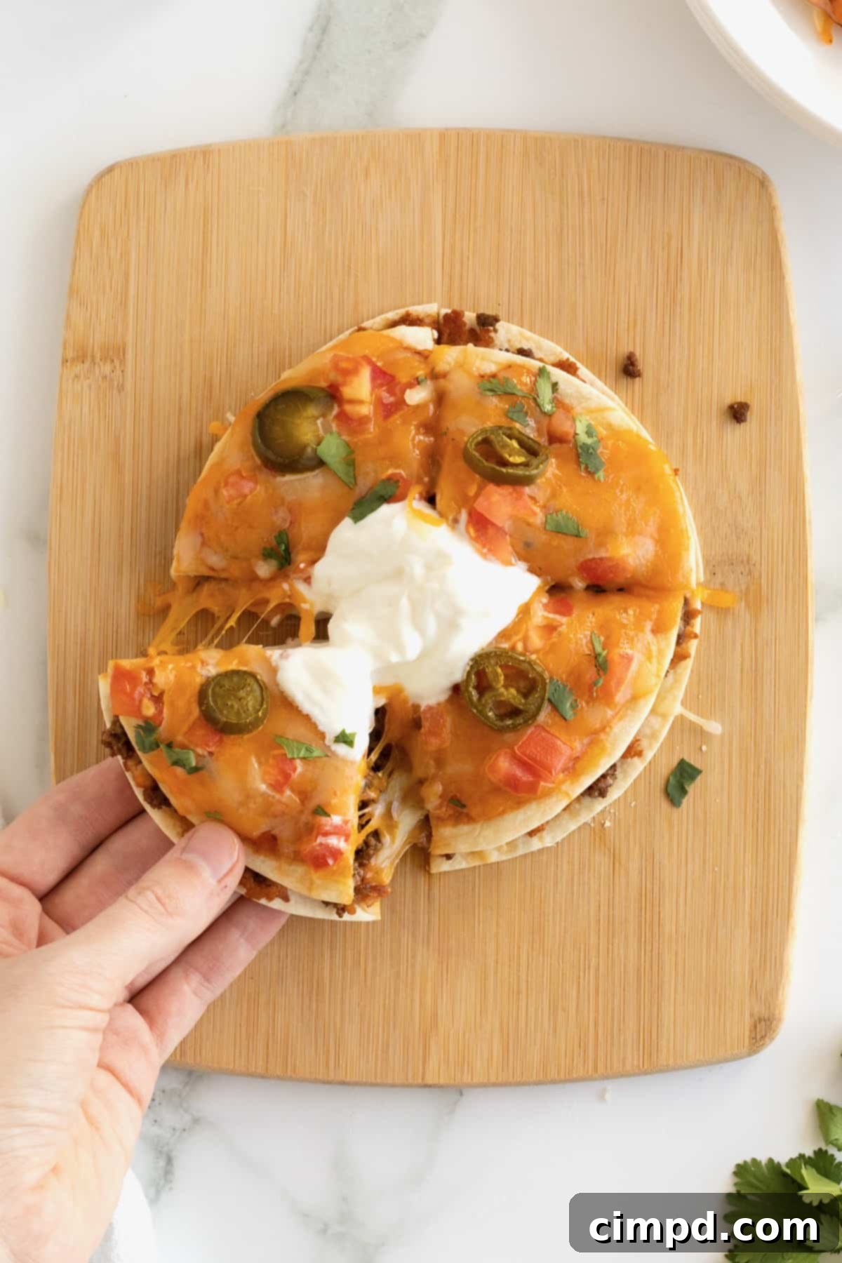 A slice out of a Mexican pizza on a wooden cutting board.