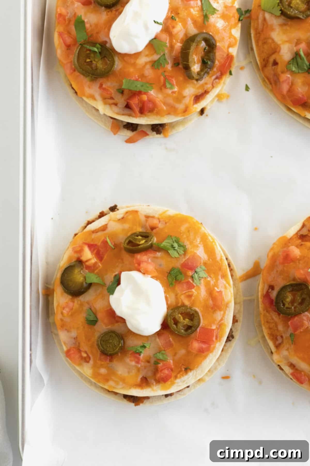 Pizzas made from tortillas with melted cheese, sliced jalapeño, and topped with sour cream.