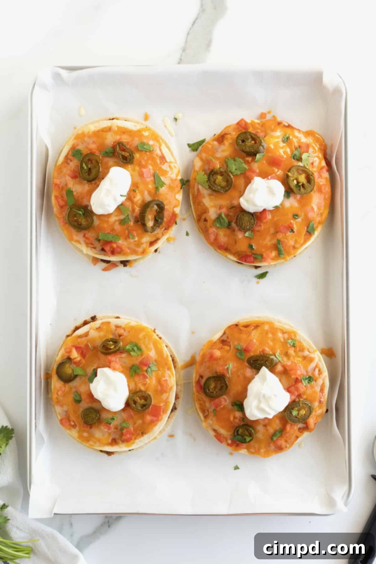 Pizzas made from tortillas with melted cheese, sliced jalapeño, and topped with sour cream.