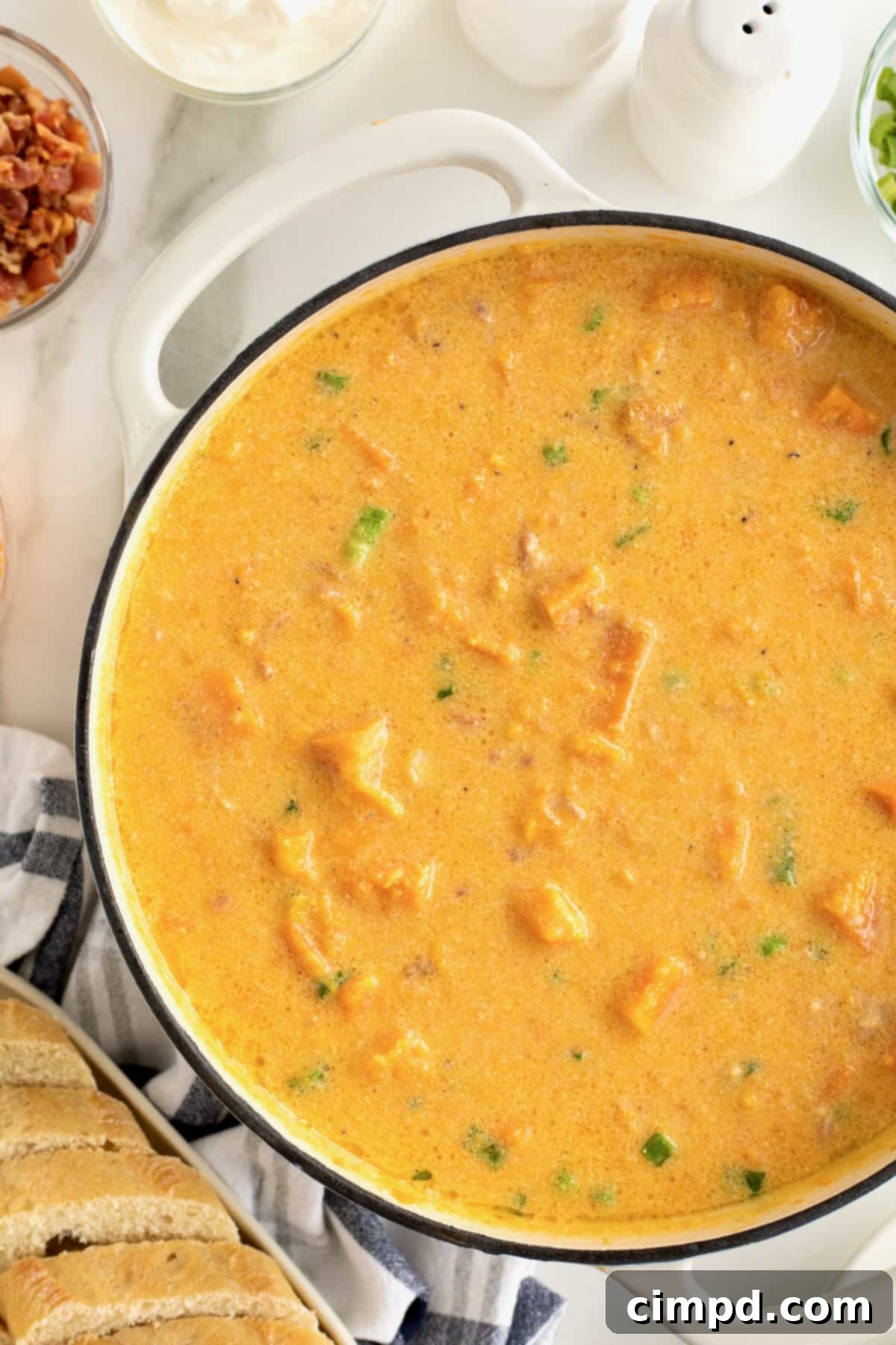 A white Dutch oven filled to the brim with a rich, creamy baked sweet potato soup, showcasing its inviting golden hue and smooth texture.