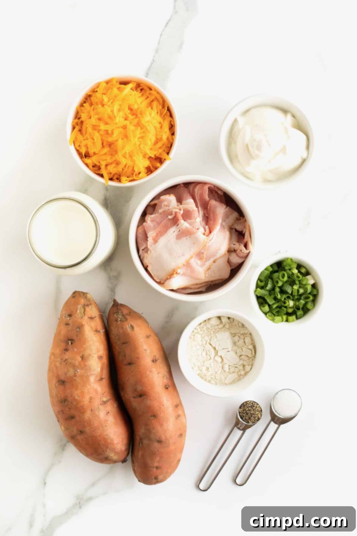 Individual glass dishes showcase the fresh ingredients for baked sweet potato soup, neatly arranged on a pristine white marble counter, including sweet potatoes, bacon, cheese, sour cream, and green onions.