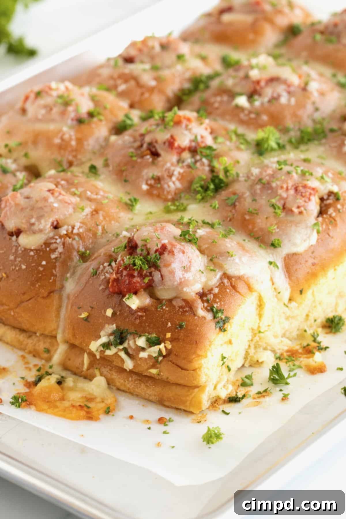 An overhead shot of freshly baked Meatball Stuffed Garlic Rolls on a baking sheet, highlighting their golden brown crust and perfectly melted cheese.