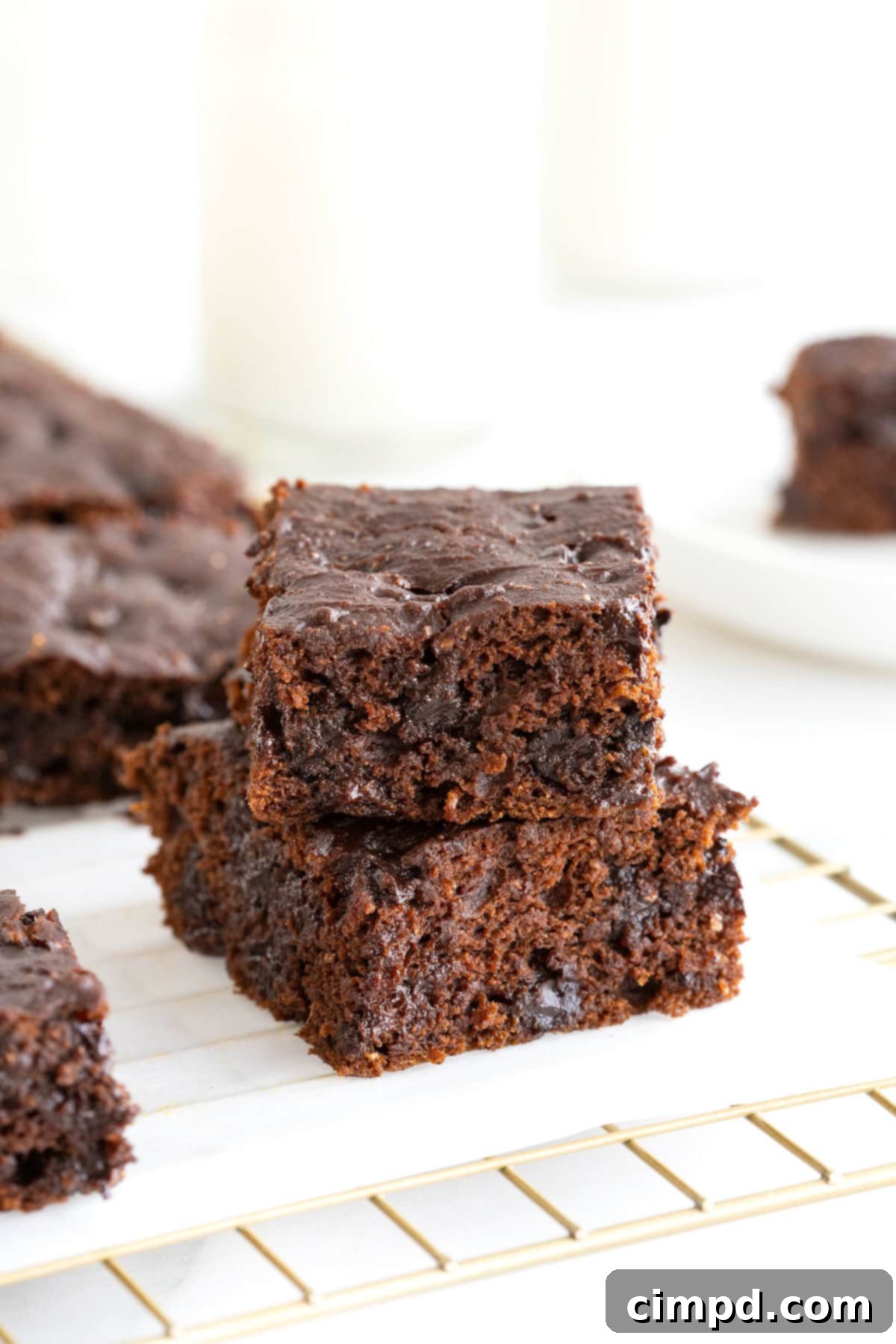Two whole wheat pumpkin brownies stacked on a parchment-lined cooling rack, showcasing their rich, fudgy texture and delicious appearance.