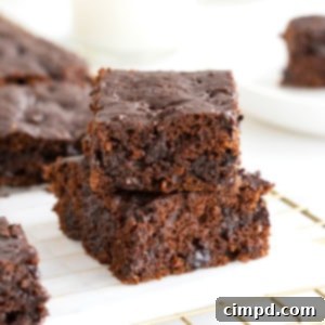 Two whole wheat pumpkin brownies stacked a parchment lined cooling rack.