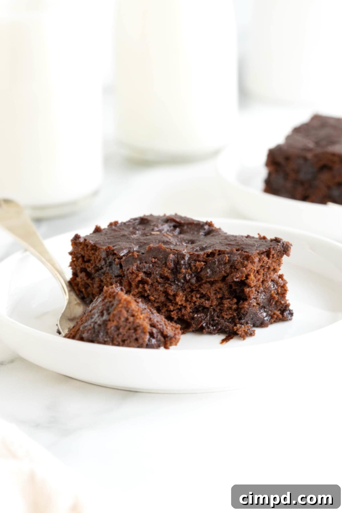 A single whole wheat pumpkin brownie, cut into a perfect square, resting on a small white plate with a metal fork, ready to be enjoyed.