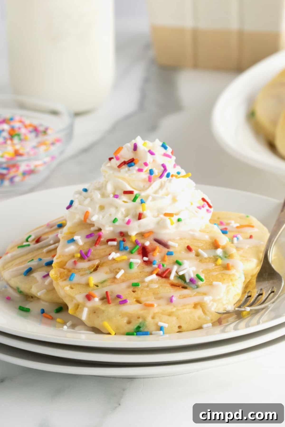 Buttermilk pancakes with colorful confetti sprinkles, topped with whipped cream and more sprinkles.