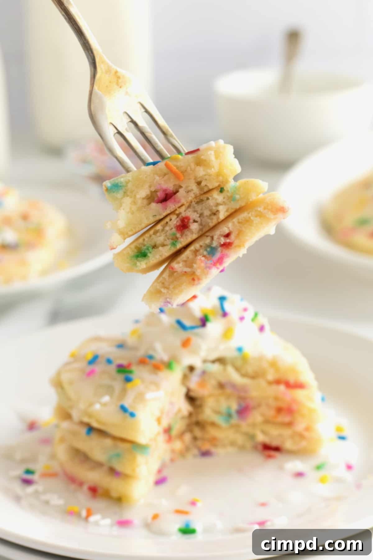 Fluffy pancakes with colorful confetti sprinkles, topped with whipped cream and more sprinkles.