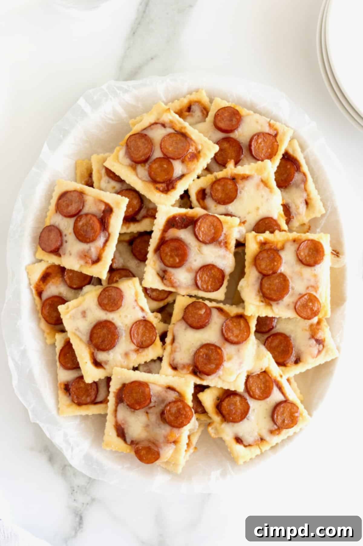Crispy Pizza Bites 6 A close-up shot of a small child's hand reaching for a freshly baked pizza cracker bite, highlighting its appeal to kids.