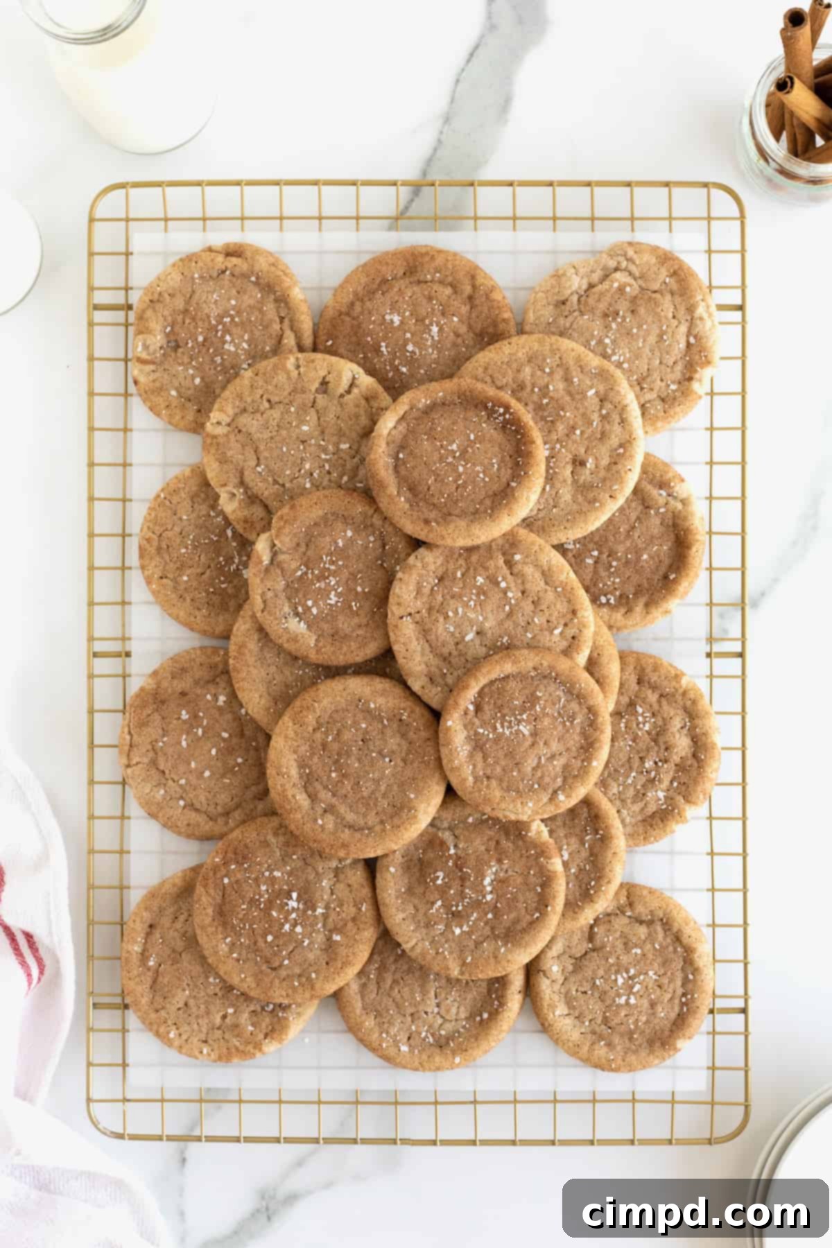 Snickerdoodle cookies sprinkled with sea salt piled on a parchment lined cooling rack.