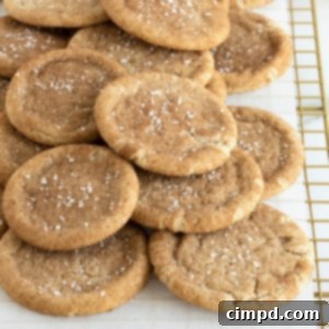 Snickerdoodle cookies sprinkled with sea salt piled on a parchment lined cooling rack.