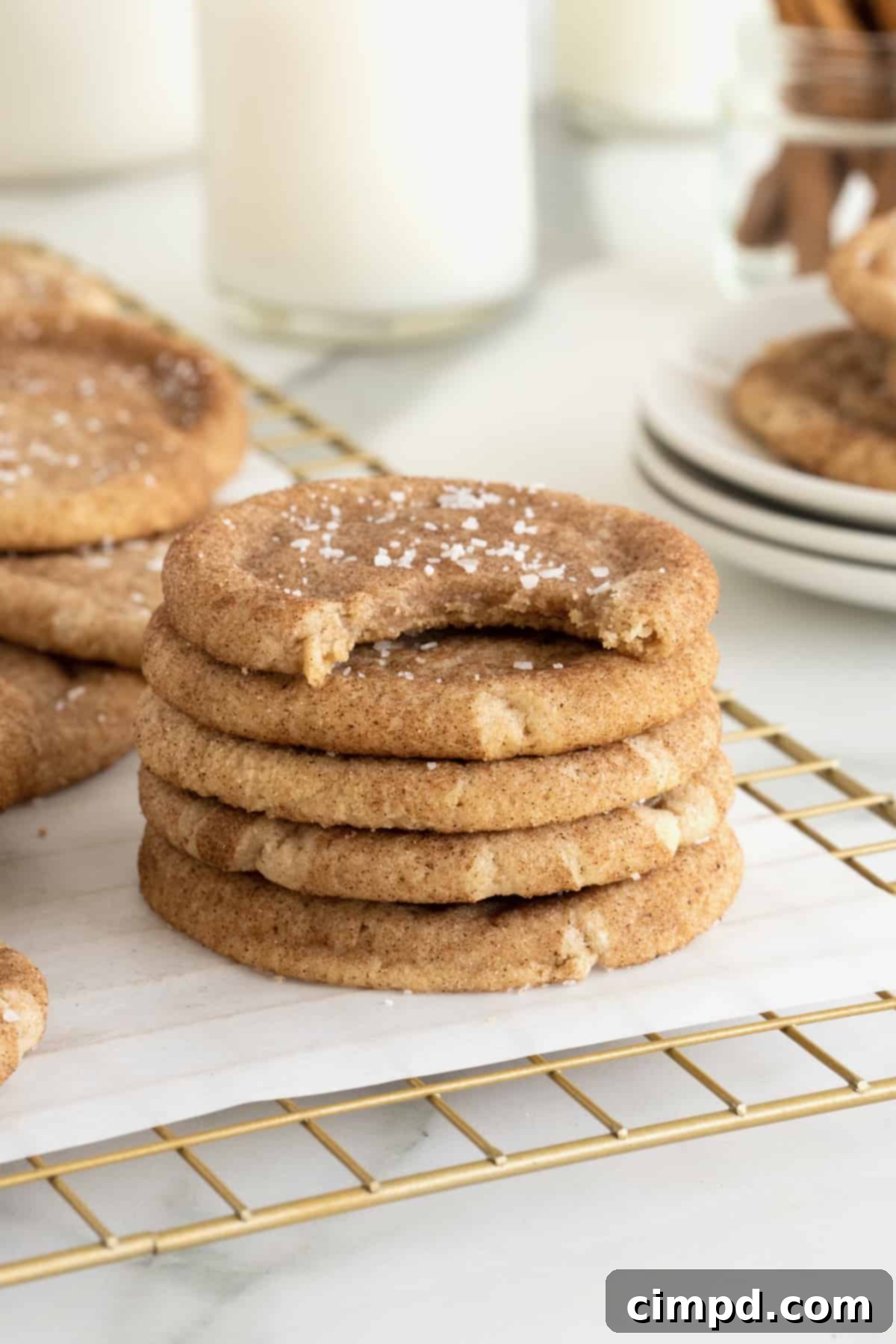 A stack of five salted brown butter snickerdoodle cookies with a bite taken out of the top cookie.